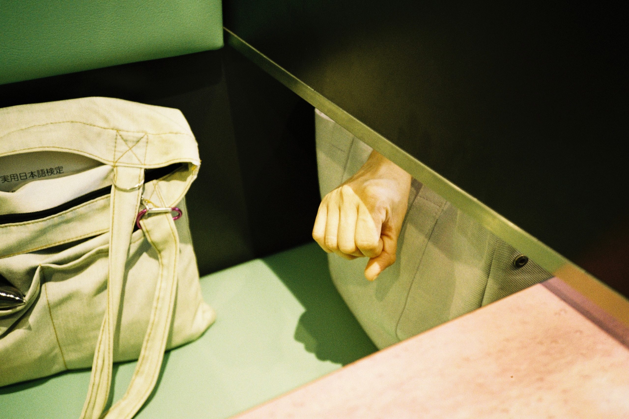 A close view of a fist resting in a jacket pocket beside a canvas bag.