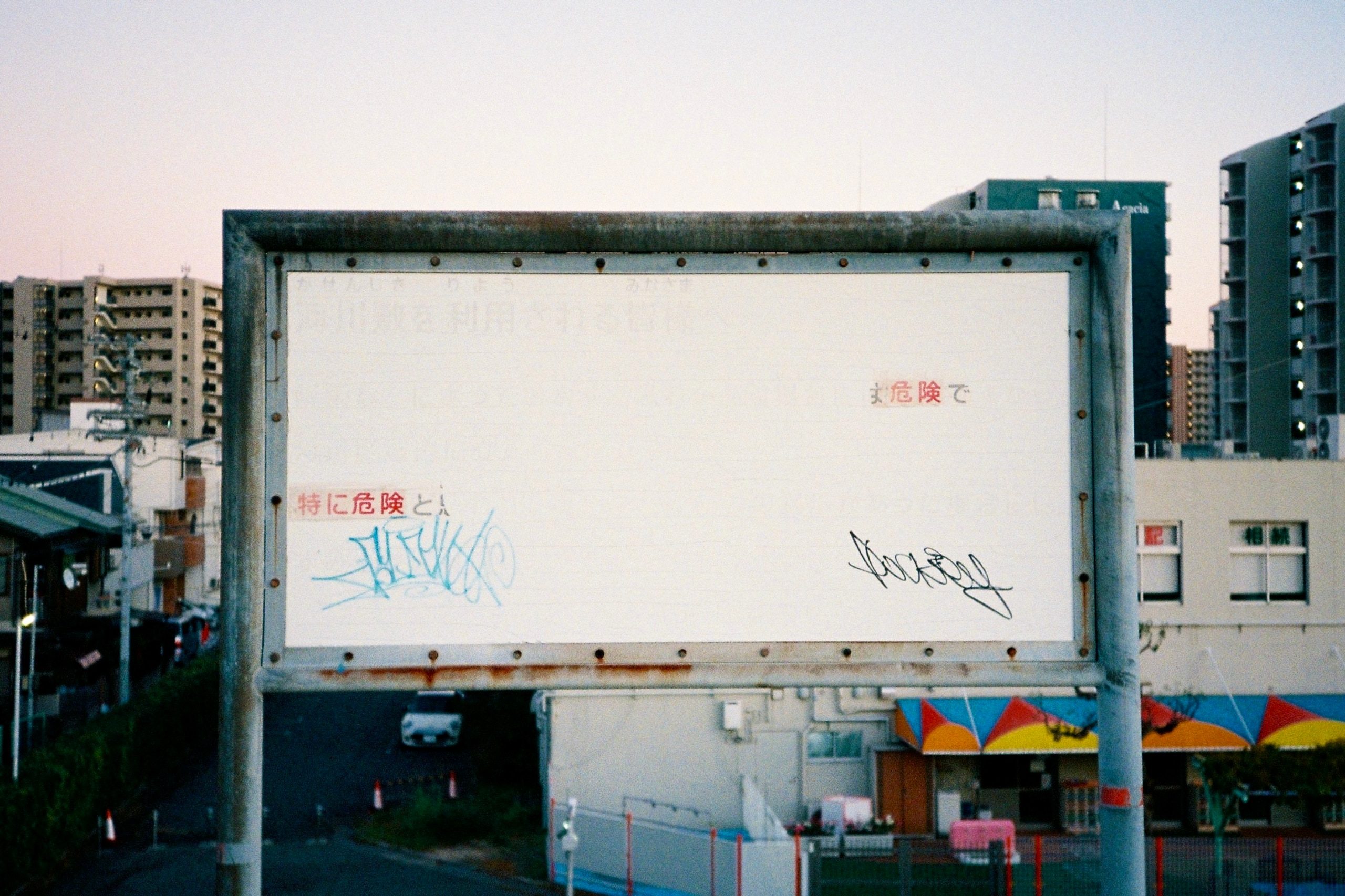 A weathered public sign, its printed warning mostly faded, marked over with graffiti scrawls.