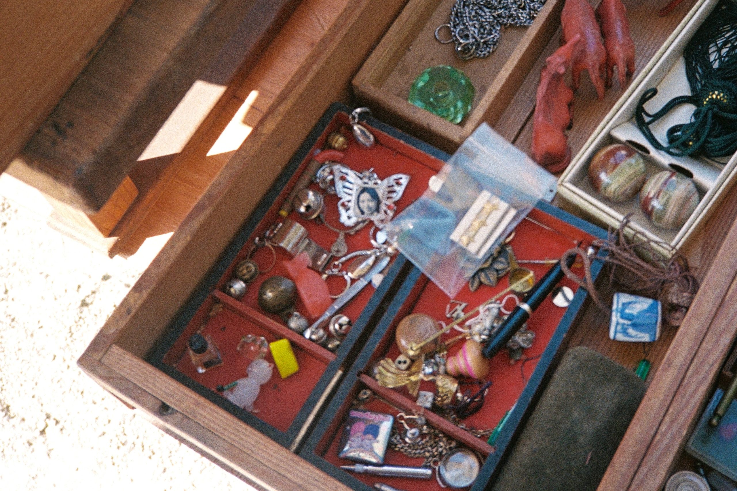 An open drawer filled with trinkets, jewelry, and small personal objects.